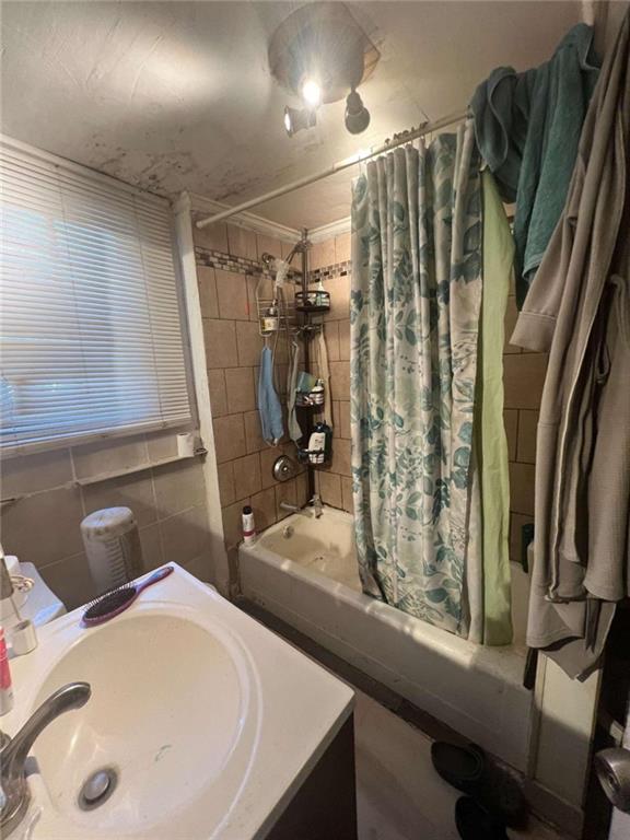 bathroom with sink, tile walls, crown molding, and shower / tub combo