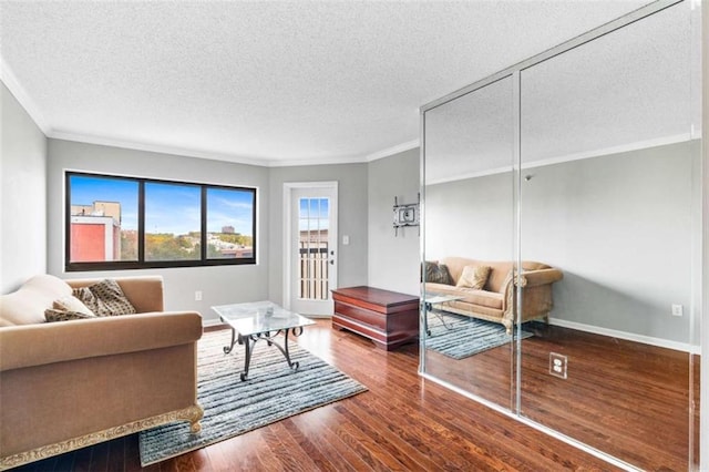 living room featuring a textured ceiling, ornamental molding, and wood finished floors