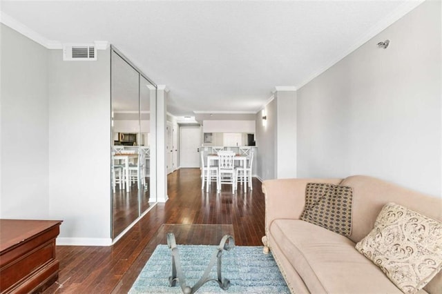 living area featuring hardwood / wood-style flooring, visible vents, ornamental molding, and baseboards