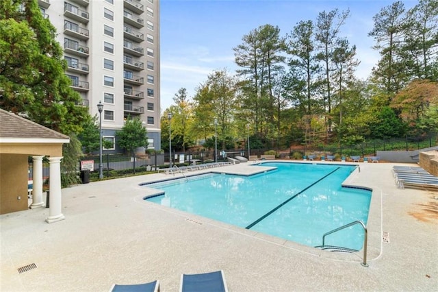 community pool with a patio area and fence