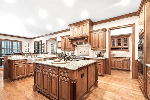 13037 Overlook Pass, Roswell, GA 30075 - kitchen with a kitchen island with sink, light wood-type flooring, crown molding, decorative backsplash, and light stone countertops