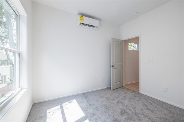 carpeted empty room with baseboards and a wall mounted air conditioner