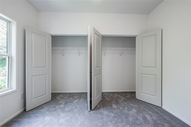 unfurnished bedroom featuring carpet, multiple closets, and baseboards