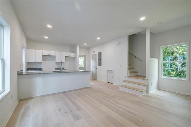 kitchen featuring light wood-type flooring, electric panel, recessed lighting, white cabinets, and stone counters