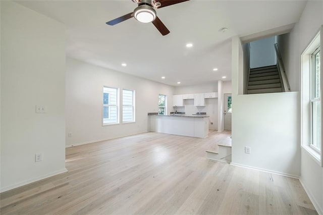 unfurnished living room featuring baseboards, stairs, recessed lighting, light wood-style floors, and a ceiling fan