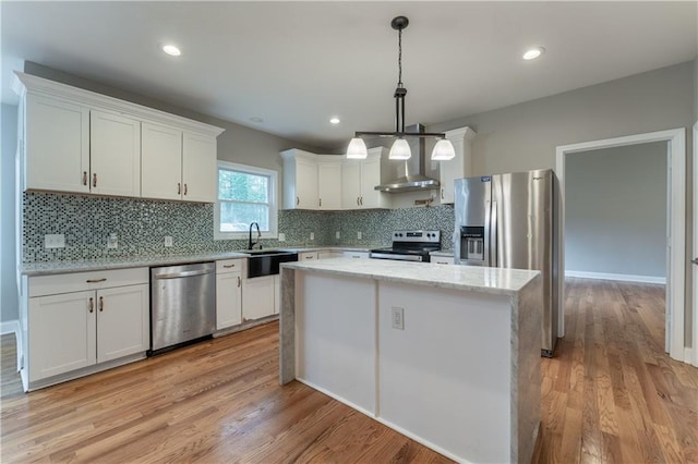 kitchen with white cabinetry, a center island, wall chimney exhaust hood, and appliances with stainless steel finishes