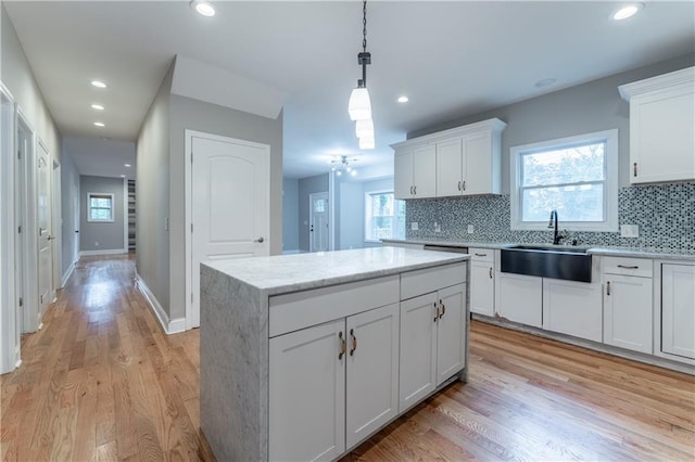 kitchen with hanging light fixtures, backsplash, white cabinets, and a kitchen island