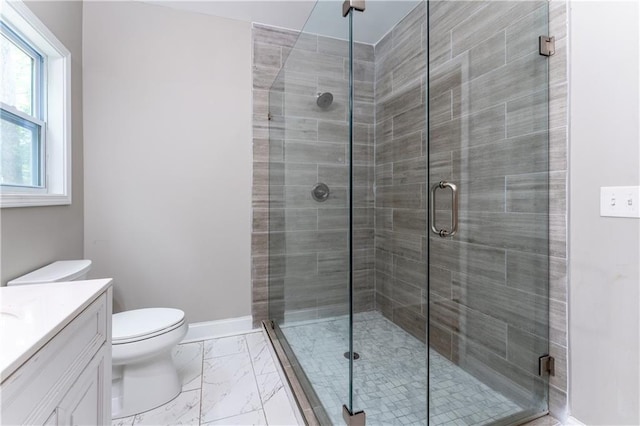 full bath with toilet, marble finish floor, a stall shower, baseboards, and vanity