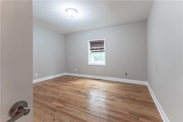 spare room with baseboards and wood finished floors