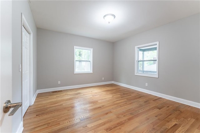 unfurnished bedroom with baseboards, multiple windows, a closet, and light wood finished floors