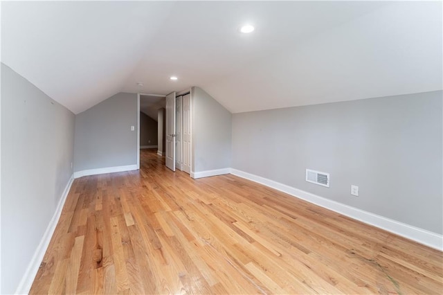 additional living space featuring vaulted ceiling and light hardwood / wood-style floors