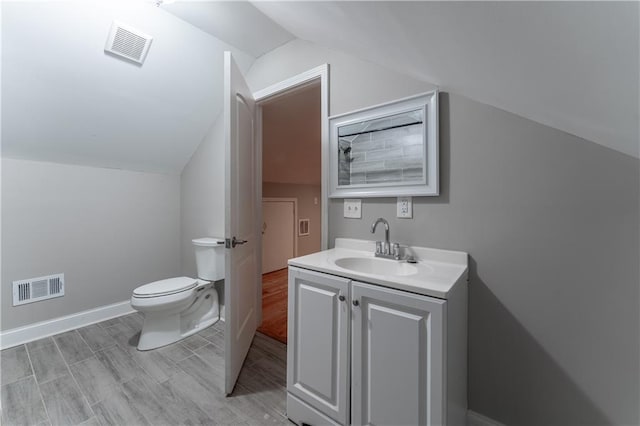 bathroom with vanity, hardwood / wood-style flooring, vaulted ceiling, and toilet