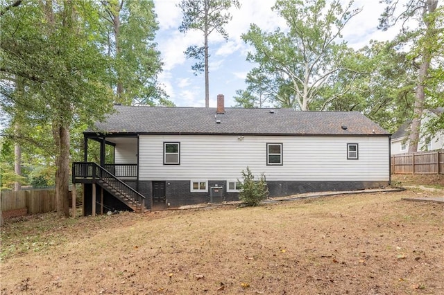 rear view of house featuring a wooden deck, central AC, and a lawn