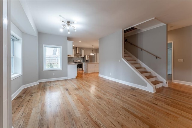 unfurnished living room featuring a notable chandelier and light hardwood / wood-style floors