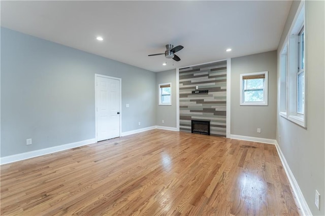 unfurnished living room featuring a fireplace, light hardwood / wood-style floors, and ceiling fan