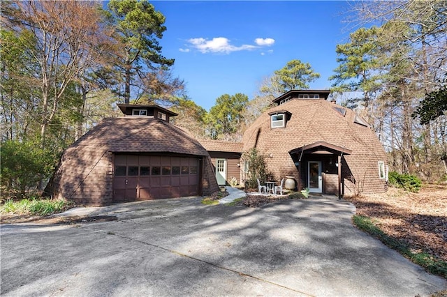 view of front of home with driveway, roof with shingles, and an attached garage