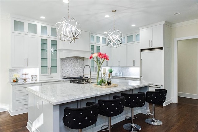 3258 Bransley Way, Duluth, GA 30097 - kitchen featuring a chandelier, dark wood-style flooring, an island with sink, decorative backsplash, and paneled refrigerator