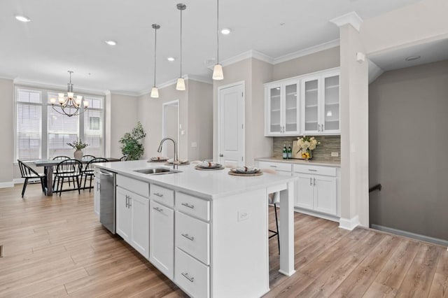 kitchen featuring a sink, stainless steel dishwasher, crown molding, light wood-style flooring, and decorative backsplash