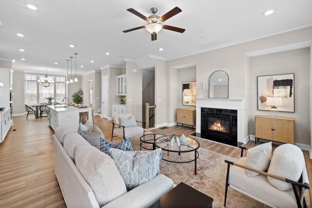 living area with crown molding, ceiling fan, recessed lighting, light wood-type flooring, and baseboards