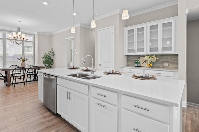 kitchen featuring dishwasher, a sink, ornamental molding, tasteful backsplash, and light wood-style flooring
