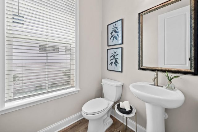 half bathroom featuring baseboards, toilet, and wood finished floors