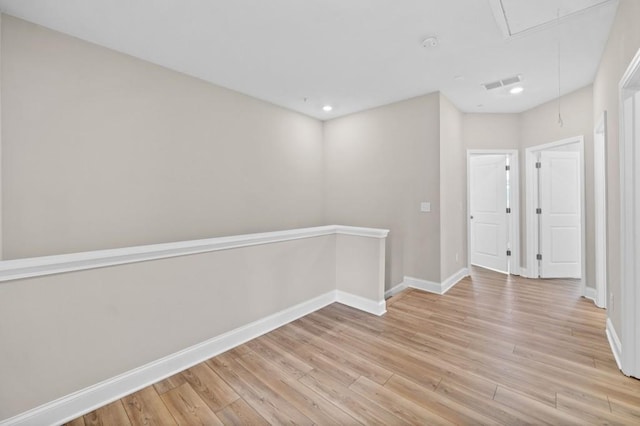unfurnished room featuring attic access, baseboards, light wood-style flooring, and recessed lighting