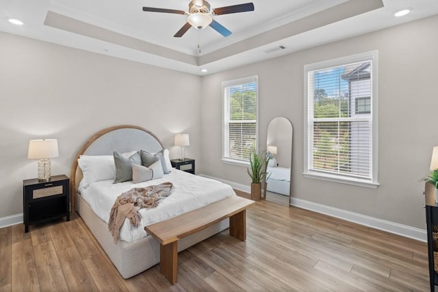 bedroom with a tray ceiling, light wood-style floors, baseboards, recessed lighting, and ceiling fan