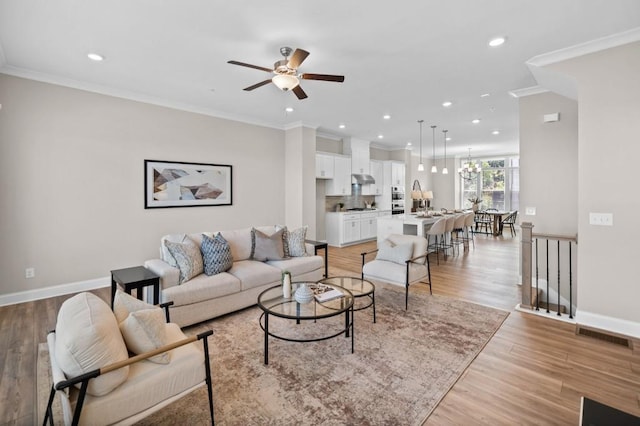 living room featuring ceiling fan, recessed lighting, baseboards, light wood finished floors, and ornamental molding