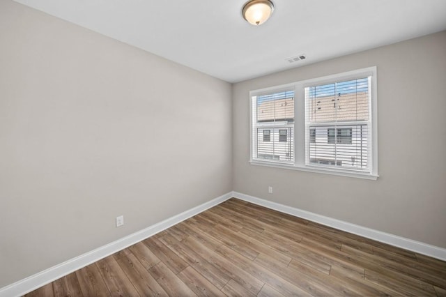 unfurnished room with baseboards and wood finished floors