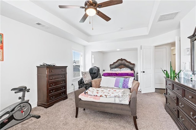 carpeted bedroom featuring a tray ceiling and ceiling fan