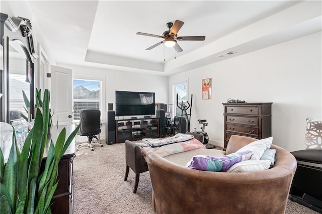 carpeted living room featuring a raised ceiling and ceiling fan