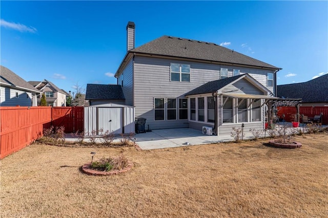 back of property with a sunroom, a yard, a patio, and a shed