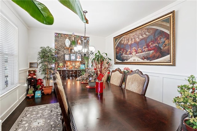 dining area with dark hardwood / wood-style flooring, an inviting chandelier, plenty of natural light, and ornamental molding