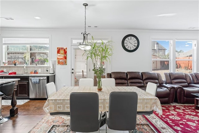 dining room featuring sink, ornamental molding, and dark wood-type flooring