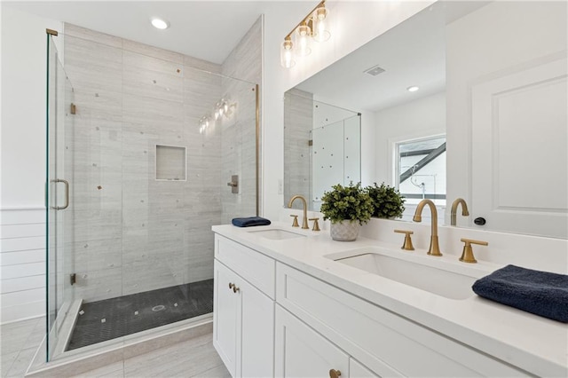 bathroom with visible vents, a sink, a shower stall, and double vanity