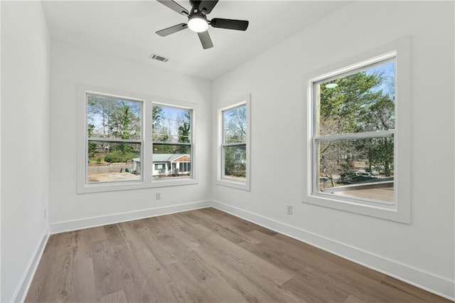 spare room featuring a ceiling fan, baseboards, visible vents, and wood finished floors