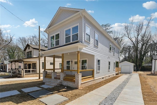 traditional style home with a detached garage, a porch, concrete driveway, and an outbuilding