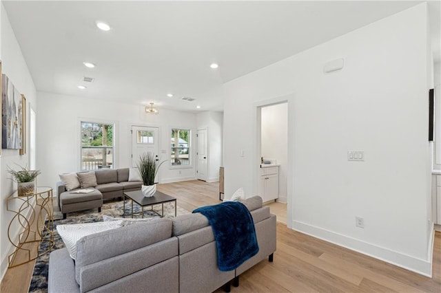 living room featuring light wood-type flooring, visible vents, baseboards, and recessed lighting