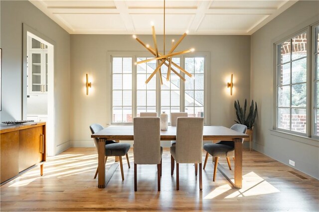 dining room with beam ceiling, coffered ceiling, an inviting chandelier, and light hardwood / wood-style flooring