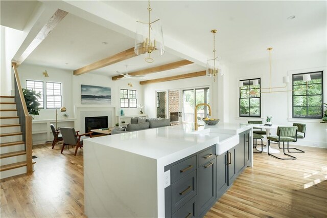 kitchen featuring an island with sink, light hardwood / wood-style floors, sink, and a wealth of natural light