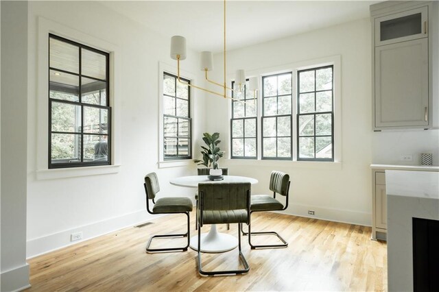 dining space featuring light hardwood / wood-style floors, a fireplace, and an inviting chandelier