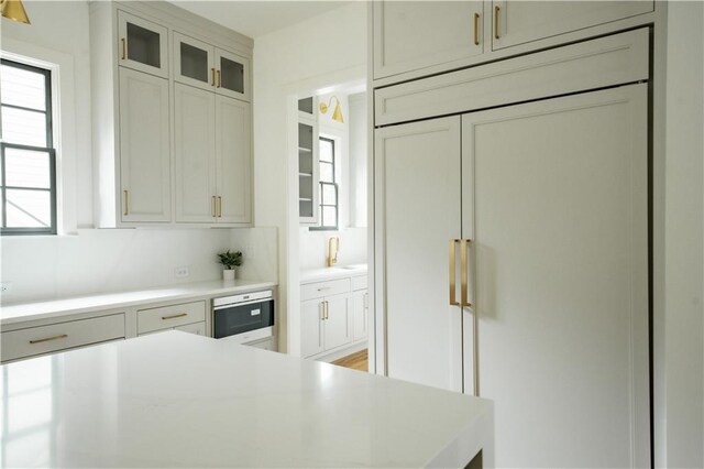 kitchen featuring sink, paneled fridge, and white cabinets