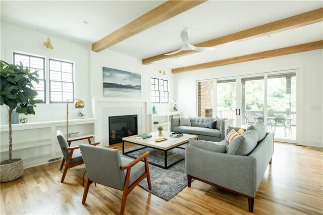 living room with beamed ceiling, light wood-type flooring, and a wealth of natural light