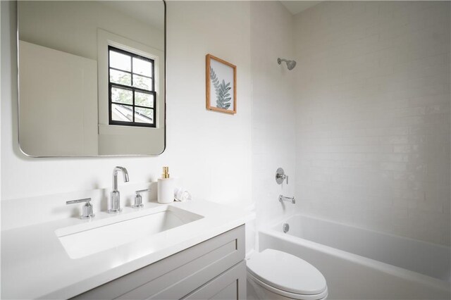 full bathroom featuring tiled shower / bath, vanity, and toilet