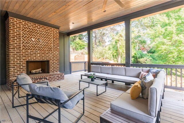 wooden terrace with an outdoor living space with a fireplace and ceiling fan