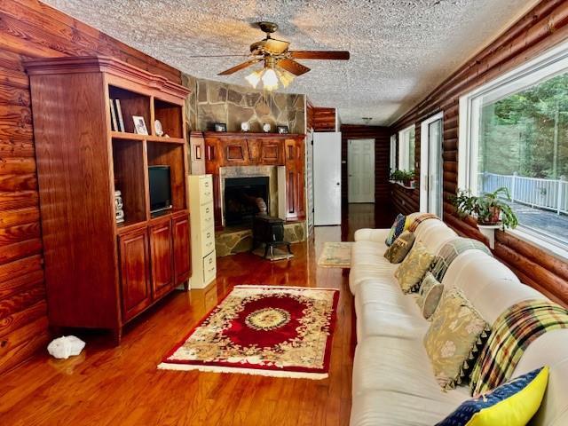 437 Apple Rdg Unit 2, Dawsonville, GA 30534 - living room featuring rustic walls, a ceiling fan, a fireplace, dark wood-style floors, and a textured ceiling