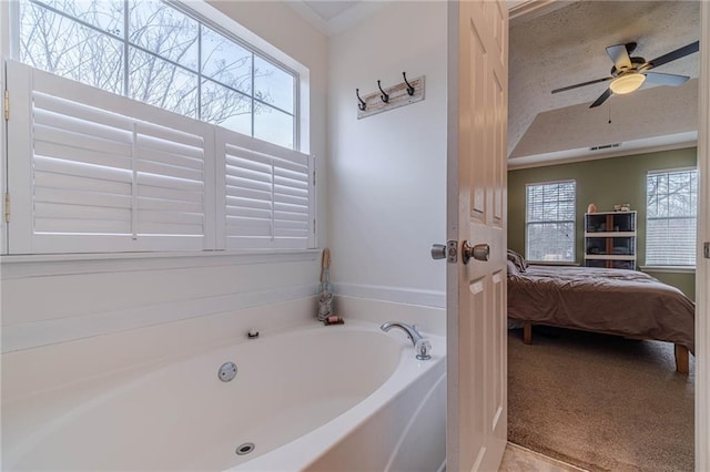 bathroom with a bathtub, a textured ceiling, and ceiling fan