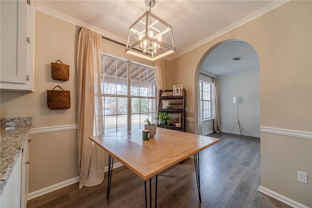 dining room with crown molding, dark hardwood / wood-style floors, a chandelier, and a textured ceiling