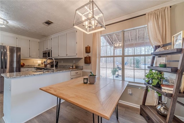 kitchen with stainless steel appliances, light stone countertops, pendant lighting, and white cabinets