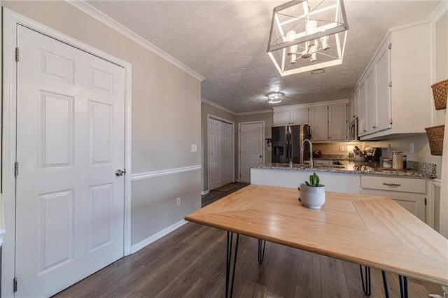 kitchen featuring decorative light fixtures, a textured ceiling, ornamental molding, dark hardwood / wood-style flooring, and stainless steel appliances